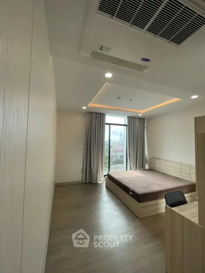 Spacious bedroom with modern design and large window offering city view