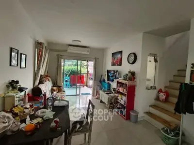 Cozy living room with dining area and balcony access, featuring modern decor and natural light.