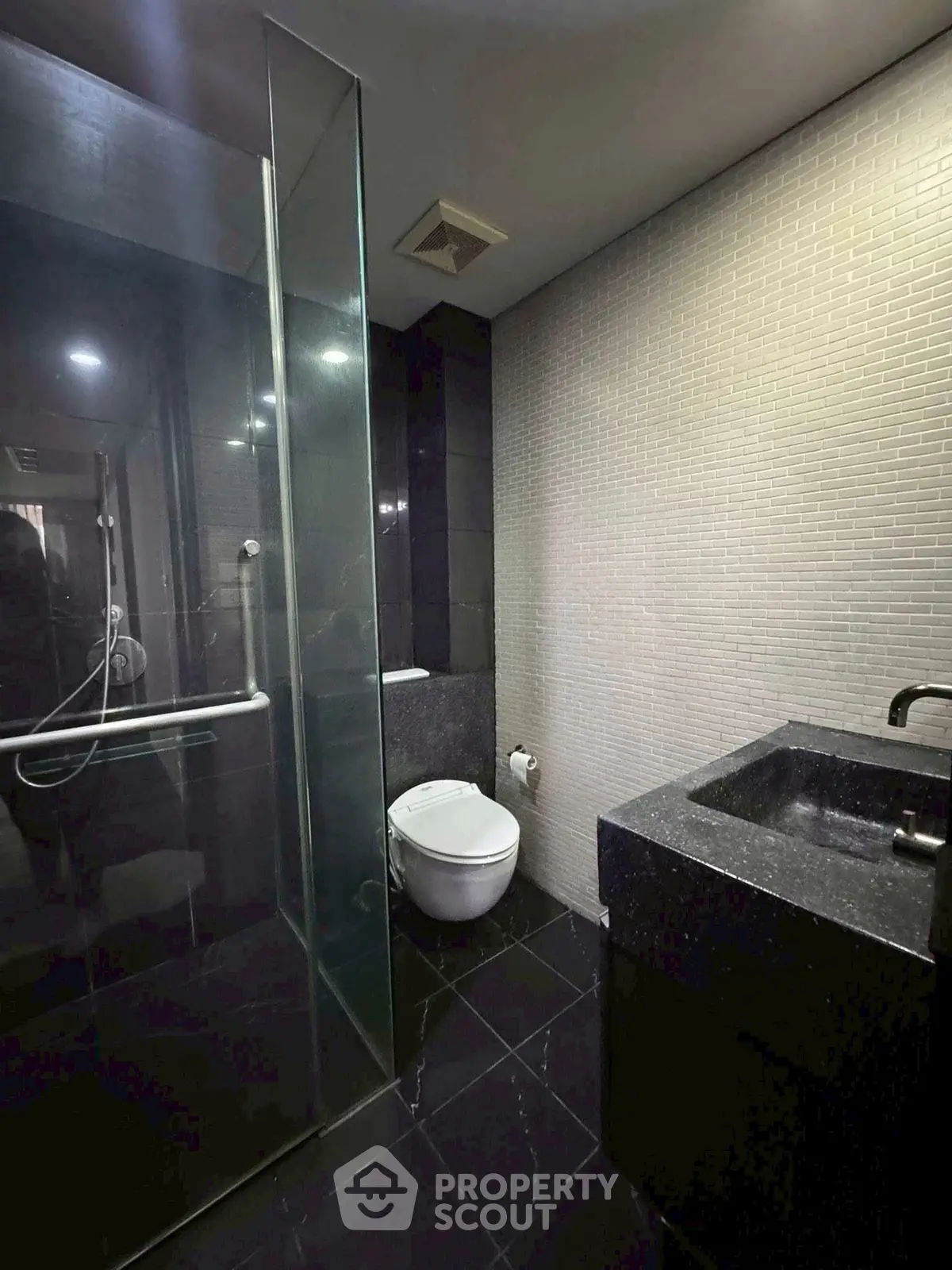 Modern bathroom with sleek black tiles and glass shower enclosure