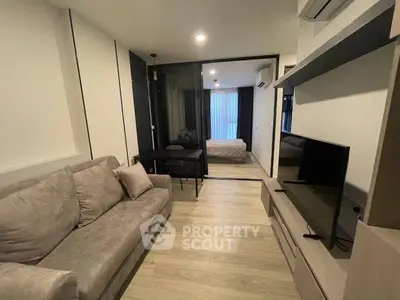 Modern living room with cozy sofa and TV, open layout to bedroom