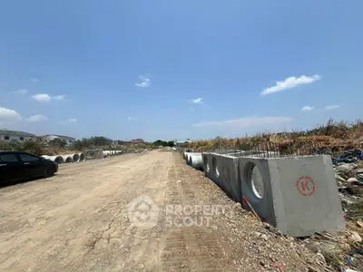 Expansive construction site with concrete pipes under a clear blue sky, ideal for development.