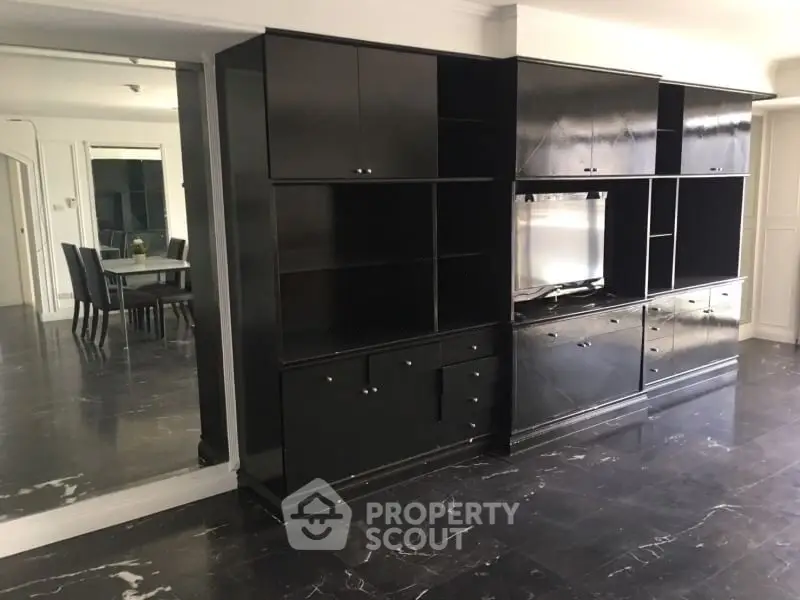 Spacious living room with sleek black cabinetry and elegant dining area, perfect for modern living.