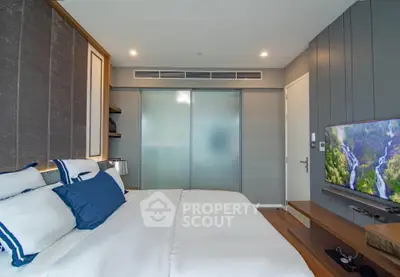 Modern bedroom with stylish decor and flat-screen TV, featuring elegant bedding and ambient lighting.