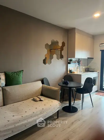 Modern living room with stylish decor and compact kitchen in open layout apartment.