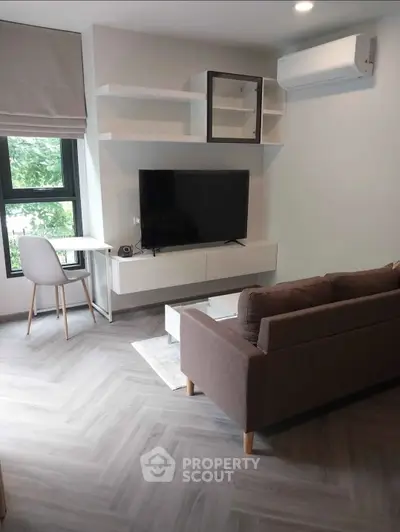 Modern living room with sleek furniture and large window offering natural light.