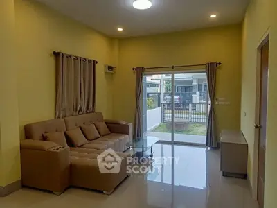 Spacious living room with modern sofa and glass door leading to garden view.