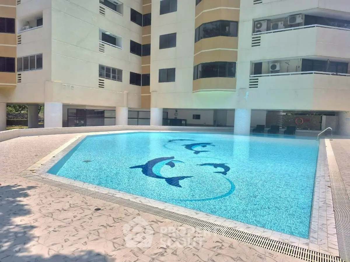 Luxurious residential building with a stunning outdoor pool featuring dolphin designs, perfect for relaxation.