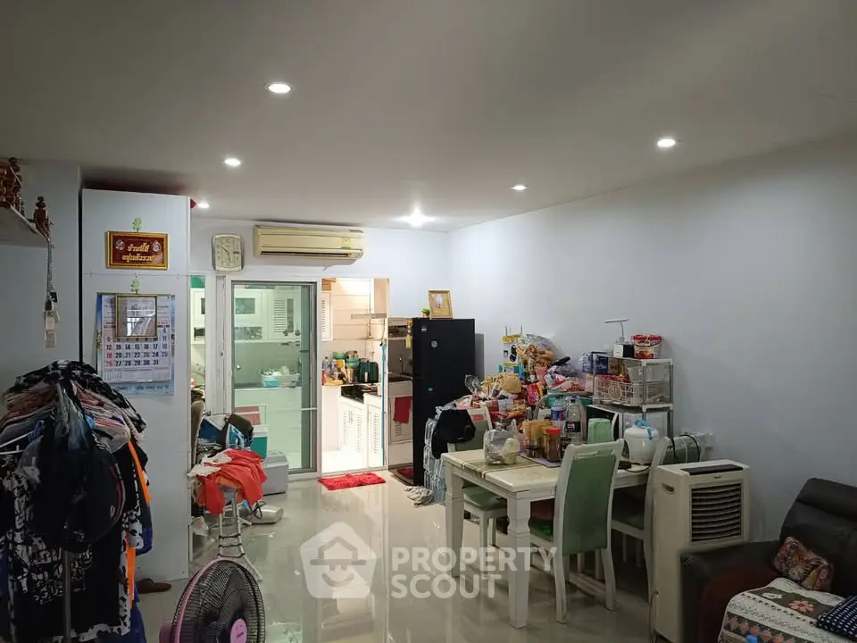 Spacious living room with modern kitchen and dining area, featuring sleek lighting and ample storage.