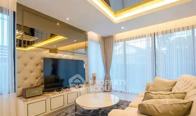Luxurious living room with modern decor and large TV, featuring elegant lighting and plush seating.