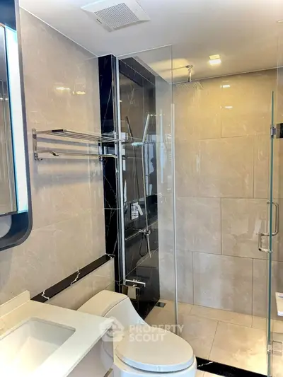 Modern bathroom with glass shower and sleek fixtures in a luxury apartment.