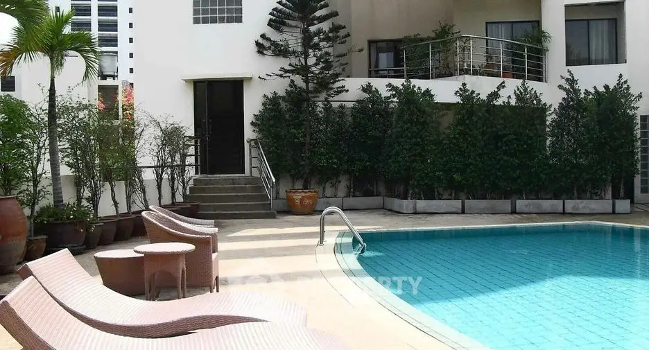 Luxurious poolside area with modern architecture and lush greenery.