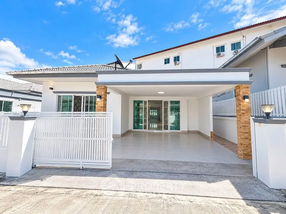 Modern house exterior with spacious driveway and gated entrance under a clear blue sky.