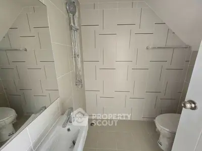 Modern bathroom with sleek tile design and bathtub in a real estate property.
