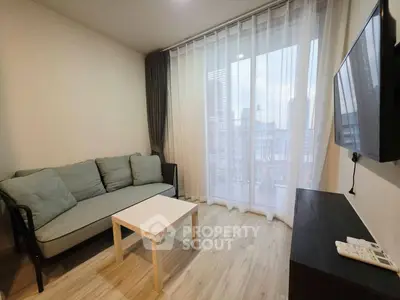 Modern living room with large window and city view, featuring a cozy sofa and wall-mounted TV.