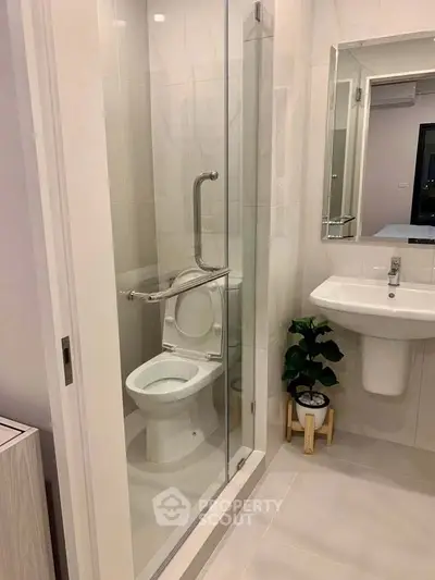 Modern bathroom with glass-enclosed toilet and sleek sink design