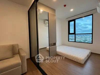 Modern bedroom with floor-to-ceiling window and city view, featuring a minimalist design and wooden flooring.