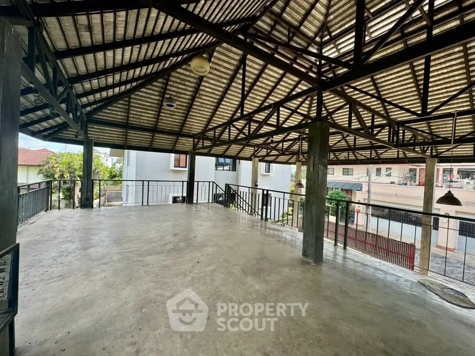 Spacious open-air rooftop with metal roofing and urban views, ideal for gatherings.