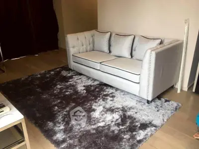 Elegant living room with plush sofa and luxurious rug, perfect for cozy relaxation.