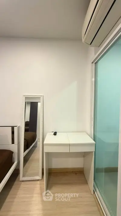 Modern bedroom corner with sleek white furniture and air conditioning, perfect for a cozy living space.
