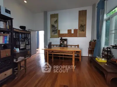 Spacious living room with wooden flooring and elegant decor, featuring large windows and ample natural light.