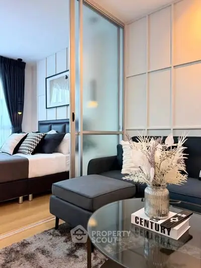 Modern living room with stylish decor and frosted glass partition leading to a cozy bedroom.