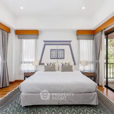 Luxurious bedroom with elegant decor and large windows offering natural light and garden view.