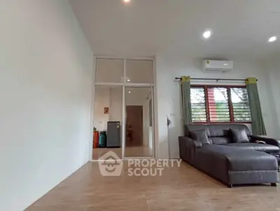 Spacious living room with modern sofa and air conditioning, featuring large windows for natural light.