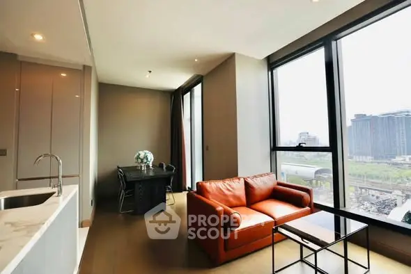 Modern living room with large windows and city view, featuring a cozy orange sofa and dining area.