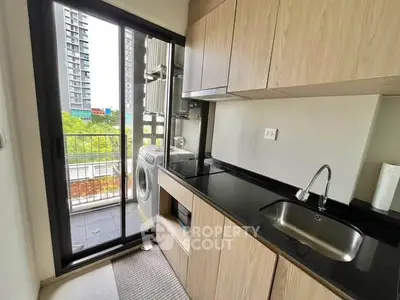 Modern kitchen with balcony view and washing machine in urban apartment