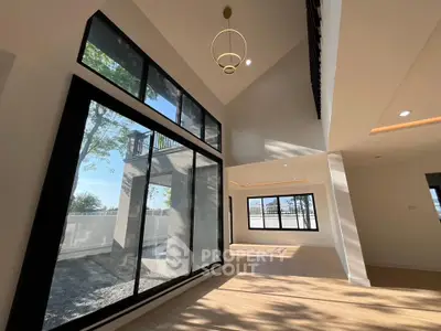 Spacious modern living room with large windows and high ceilings, offering abundant natural light and outdoor views.