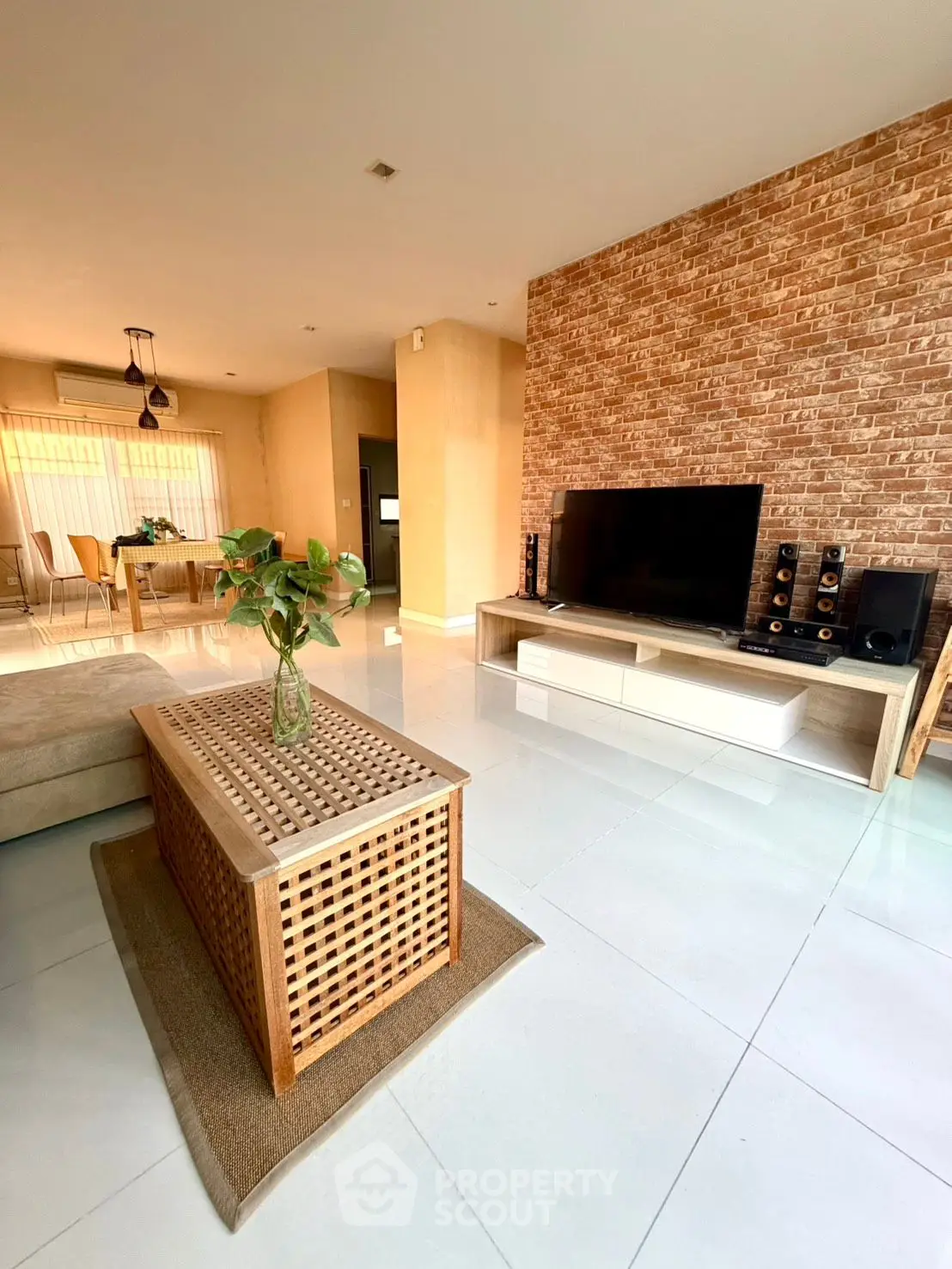 Spacious modern living room with brick accent wall and sleek entertainment center.