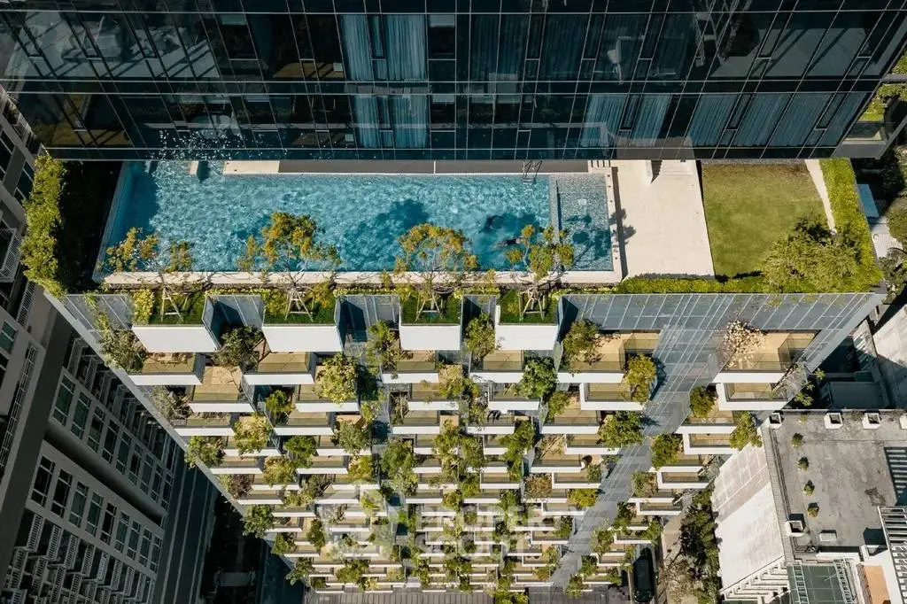 Stunning rooftop pool with lush greenery on modern high-rise building.