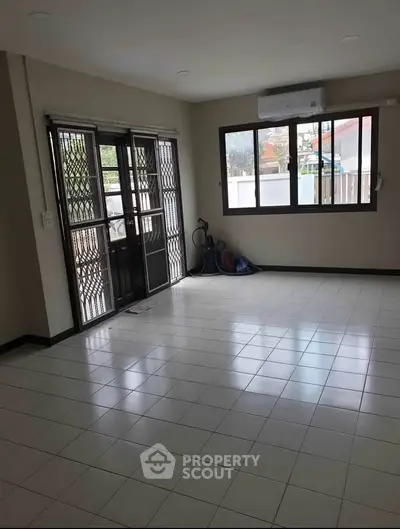 Spacious living room with tiled floor and large windows in a modern home.