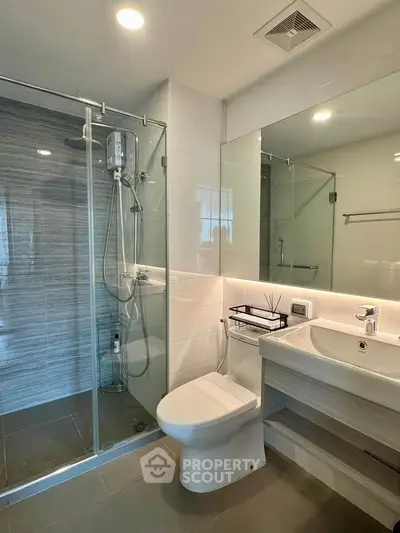 Modern bathroom with glass shower and sleek fixtures in contemporary apartment.