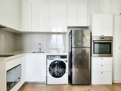 Modern kitchen with sleek appliances including washing machine, fridge, and built-in oven in a bright setting.
