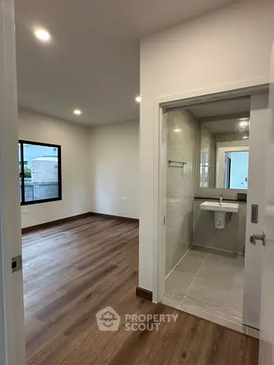 Modern apartment interior with sleek bathroom and spacious room, featuring elegant wood flooring.