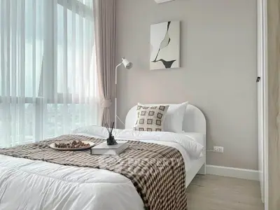 Modern bedroom with large window and stylish decor in a high-rise apartment.