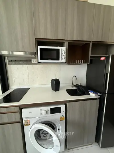 Modern kitchen with washing machine, microwave, and sleek cabinetry