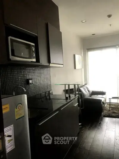 Modern compact living room with sleek kitchen and dark wood flooring