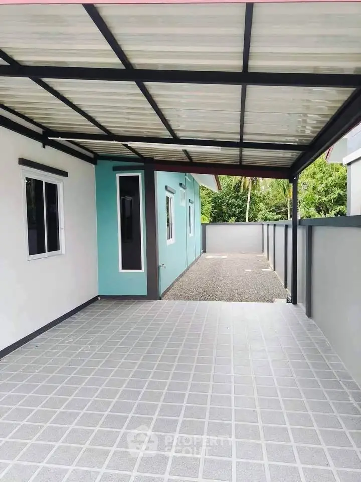 Modern home exterior with covered carport and tiled driveway, offering sleek design and ample parking space.