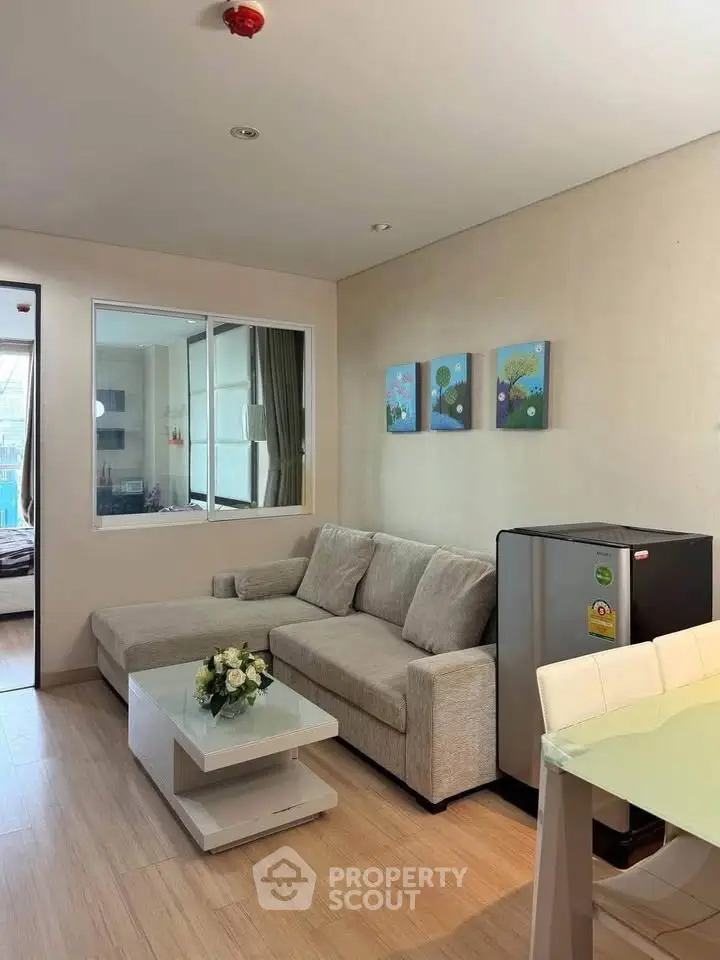 Modern living room with cozy sofa, stylish decor, and compact fridge in a contemporary apartment.