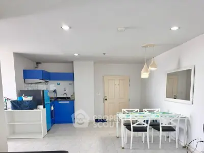 Modern open-plan living area with blue kitchen cabinets and stylish dining set.