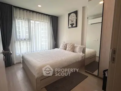 Modern bedroom with large window and stylish decor in a contemporary apartment.