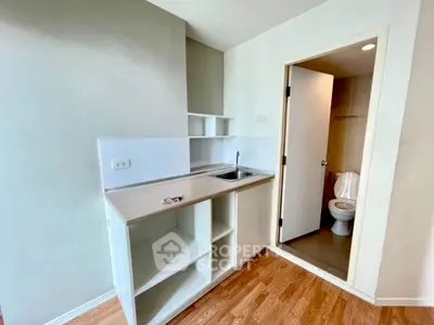Compact kitchenette with adjacent bathroom in modern apartment