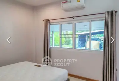 Cozy bedroom with air conditioning and large window offering natural light and garden view.