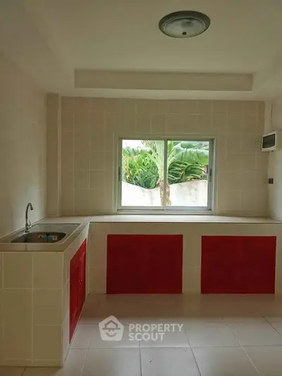 Bright kitchen with red cabinets and garden view window