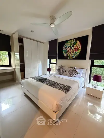 Modern bedroom with stylish decor and large windows offering natural light.