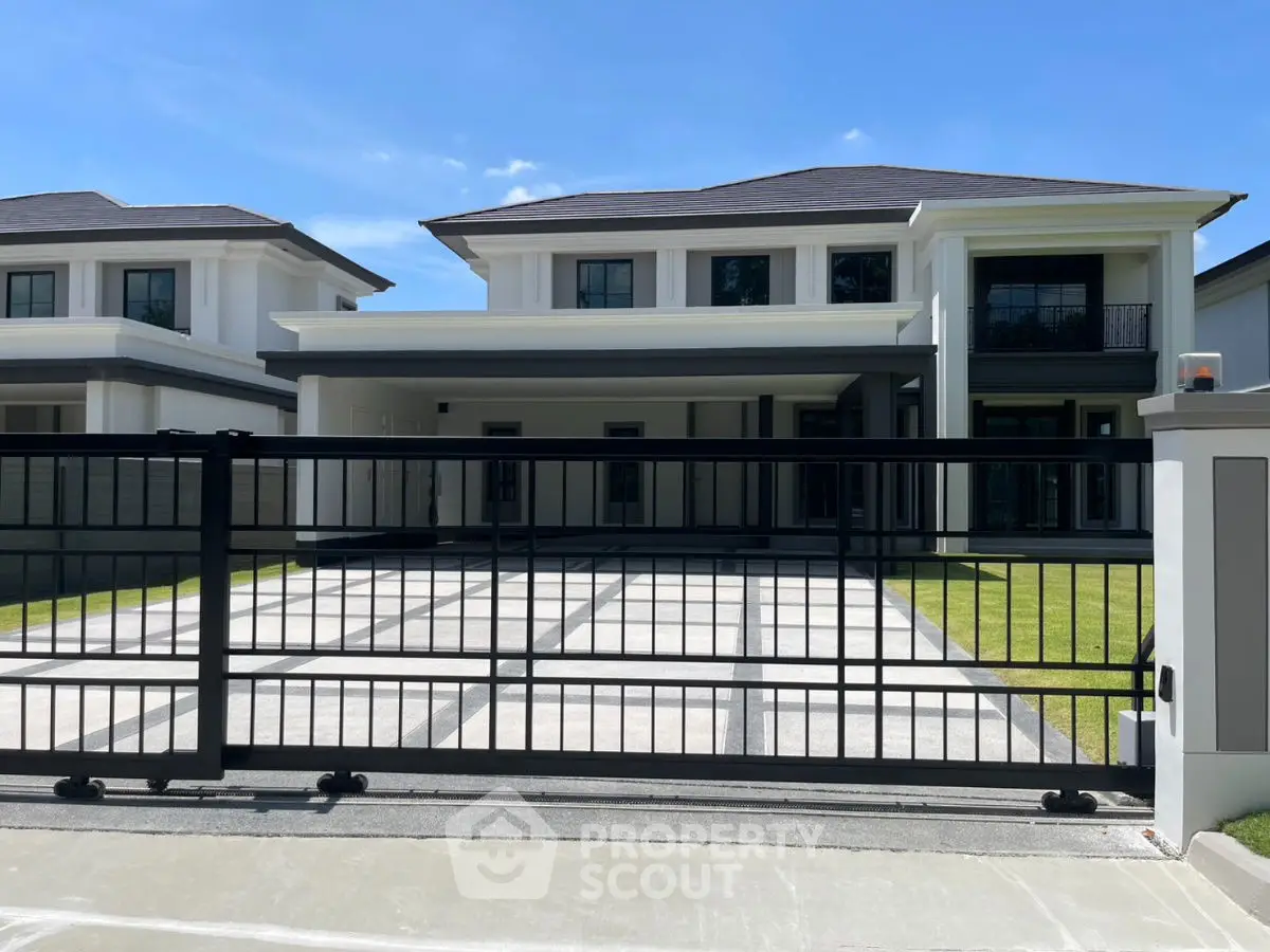 Luxurious modern house with spacious driveway and elegant facade under clear blue sky.