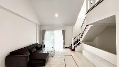 Spacious modern living room with sleek black sofa and elegant staircase