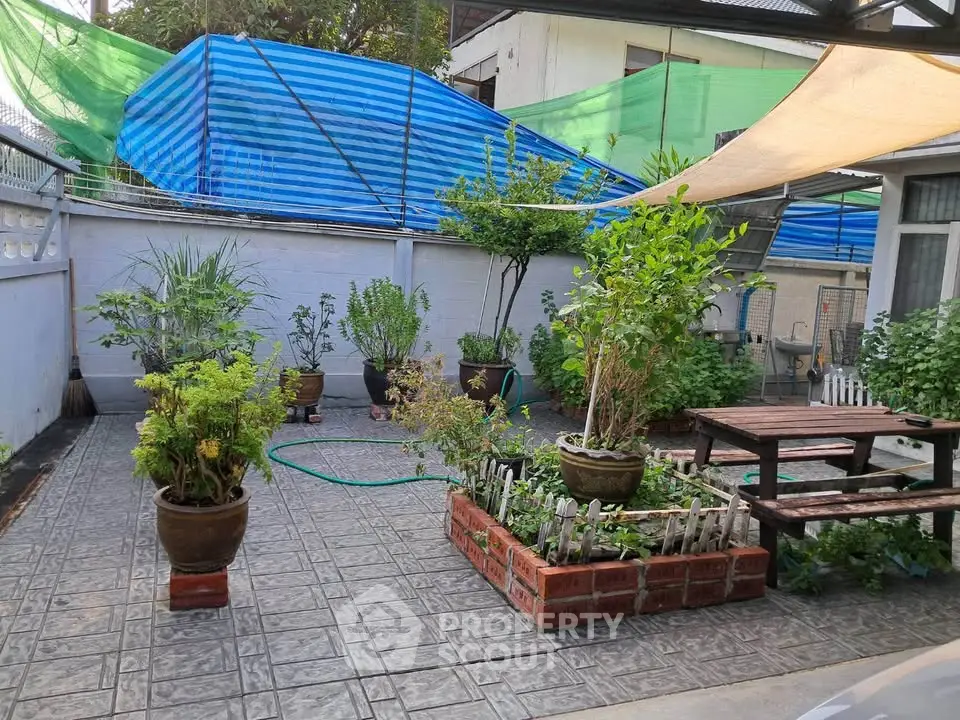 Charming garden patio with lush plants and cozy seating area, perfect for outdoor relaxation.